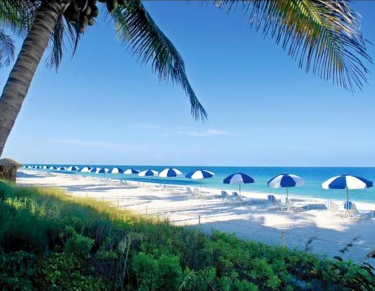 Blue and white beach umbrellas on a Naples beach